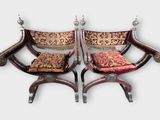 une paire de chaises ornées de coussins rouges et dorés, sur fond blanc