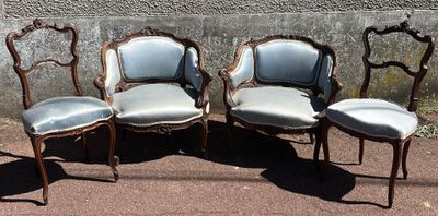 four antique chairs are lined up against a concrete wall