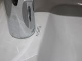 a white sink with a chrome faucet and a soap dispenser
