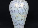 un vase blanc et bleu posé sur une surface noire