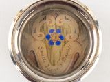 a small silver pocket watch with a blue flower on it