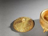 a gold bowl with a lid sitting on a table