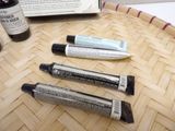 three tubes of cream sitting on a table next to an open book