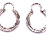 une paire de boucles d'oreilles créoles en argent sur fond blanc