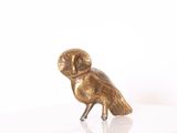 une figurine de chouette en or posée sur une table blanche