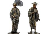 pair of antique bronze figurines of a man and a woman holding an umbrella