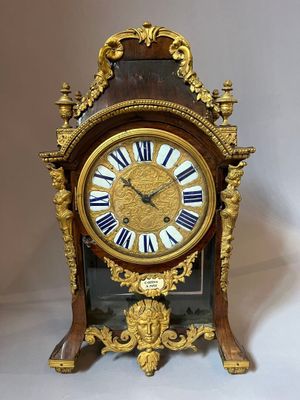 a gold clock with roman numerals on the face