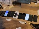 de nombreux téléphones portables posés sur une table, avec un ordinateur portable en arrière-plan