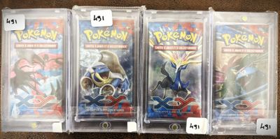 trois paquets de cartes à collectionner Pokémon dans des pochettes en plastique, posés sur une table