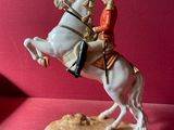 figurine représentant un homme à cheval sur un fond rouge