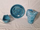 three pieces of pottery sitting on a white surface
