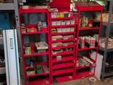 a red shelving in the middle of a room filled with items