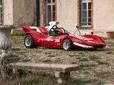 une voiture de course rouge garée devant un immeuble