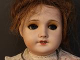 a close up of a doll with a necklace on it