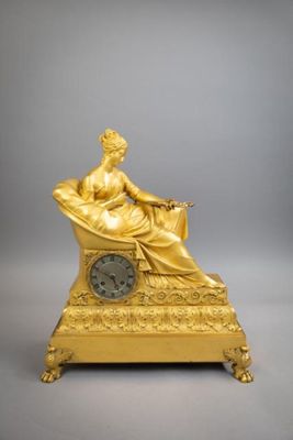 statue en or représentant une femme assise sur une chaise, avec une horloge devant elle