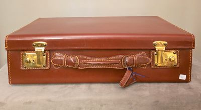 une valise marron posée sur une table, avec une clé à l'intérieur