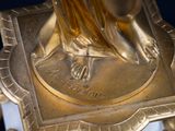 a gold statue of a woman on a marble base