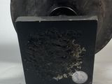 a black vase sitting on a white surface next to a coin