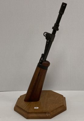 un fusil posé sur un support en bois, sur une surface blanche