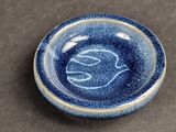 a blue plate with a bird on it on a table