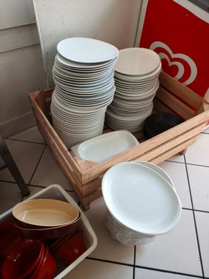 de nombreuses assiettes et bols rangés dans une caisse en bois posée par terre