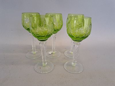 quatre verres à vin verts posés sur une surface blanche