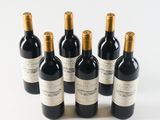 six bottles of wine are lined up in a row on a white surface