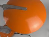 an orange table lamp with a cord plugged to the base