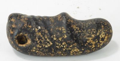 un objet en pierre percé d'un trou, posé sur une surface blanche