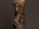 bronze sculpture of a man sitting on a rock with his back to the camera