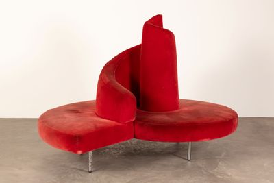 an image of a red chair with a curved seat on a concrete floor