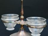 a silver candle holder with three glass bowls on top of it