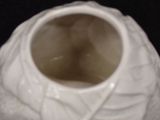 a white vase with a leaf design on it