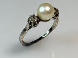 an image of a pearl and diamond ring on a white surface