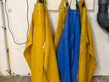 yellow and blue aprons hanging up against a wall in a garage