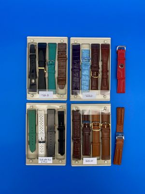 quatre montres différentes dans un coffret, avec des bracelets en cuir, sur fond bleu