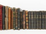 several old books are lined up in a row on a white surface