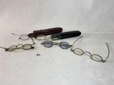 trois paires de lunettes et un stylo posés sur une surface blanche