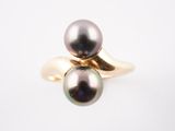 une bague en or sertie d'une perle noire sur fond blanc