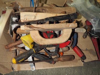 une boîte remplie d'outils et un marteau posé par terre