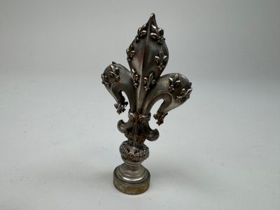 an antique silver fleuret on a pedestal with a white background
