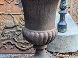 a large urn sitting on the ground next to a fence