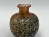 a brown and black vase sitting on a white surface