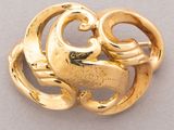 an image of a gold brooch with swirls on it