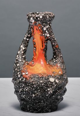 un vase noir et orange posé sur une table