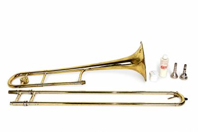 le trombone est posé sur une surface blanche, à côté d'autres instruments de musique