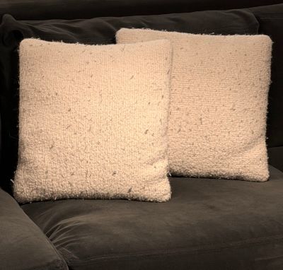 two white pillows sitting on top of a couch next to each other