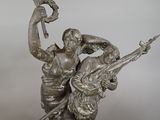 bronze statue of a man and woman holding a bird on a rock