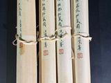 quatre livres enroulés, portant des inscriptions en chinois, posés sur une table