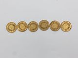 a row of five gold coins sitting on top of a white surface